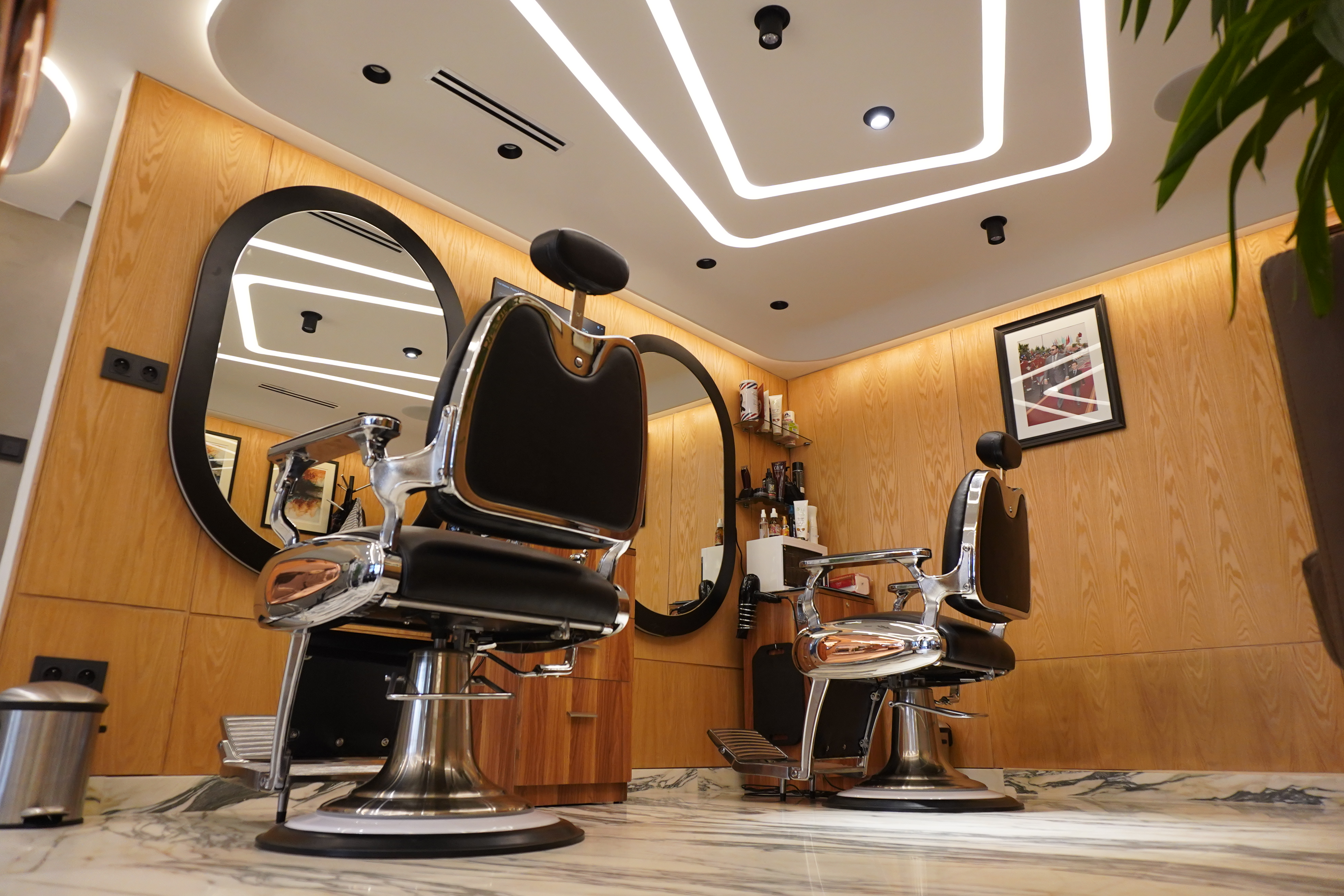 Barber shop contemporain avec fauteuils, boiseries et éclairage architectural